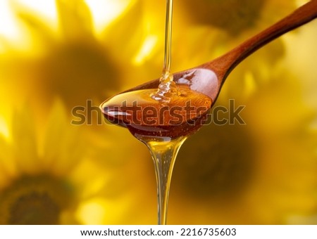 honey flows from a wood spoon against a bokeh background of sunflower flowers in the fog. advertising concept.
