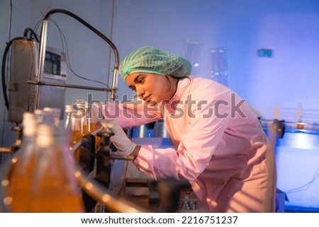 Woman Quality Control a fruit drink factory in glass bottles Inspecting glass bottle packaging for fruit juice drinks, Worker QC working in a drink water factory. Royalty-Free Stock Photo #2216751237