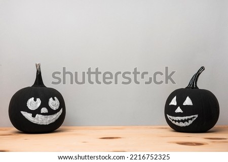 Halloween celebration. Black pumpkins with drawn spooky faces on wooden table, space for text