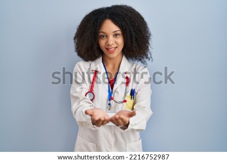 Young african american woman wearing doctor uniform and stethoscope smiling with hands palms together receiving or giving gesture. hold and protection 