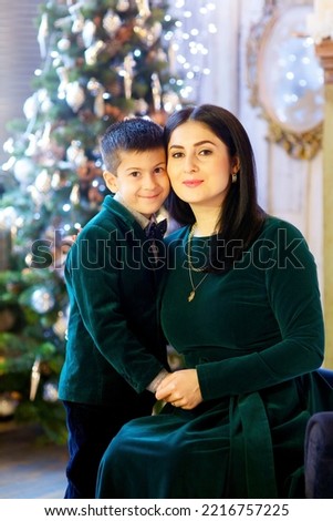 A little boy and her mother in festive attire are in a room decorated for the New year and Christmas. The concept of holidays and gifts.