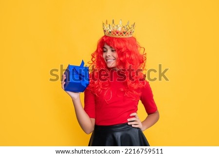 cheerful child in diadem with present box on yellow background