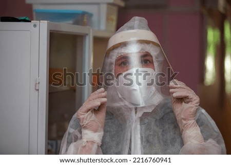 The face of a female doctor close-up in a protective suit.