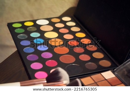 Photo of multi-colored makeup stylist's palette and bones in the foreground in defocus