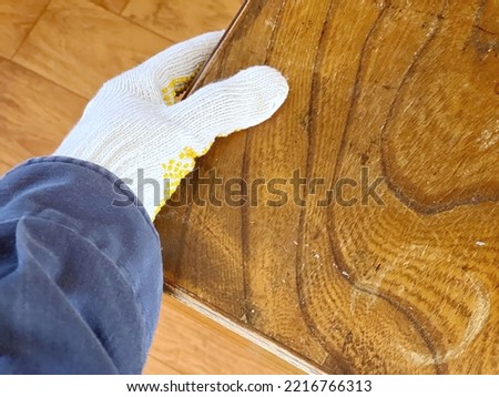 Gloved hand holding an old wooden table Royalty-Free Stock Photo #2216766313