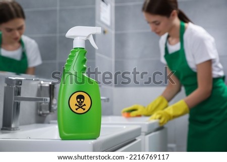 Spray of toxic household chemical with warning sign in bathroom