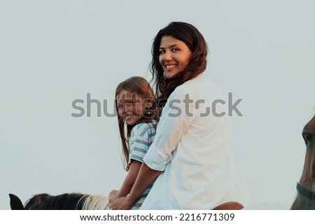 Mother and daughter enjoy riding horses together by the sea. Selective focus 