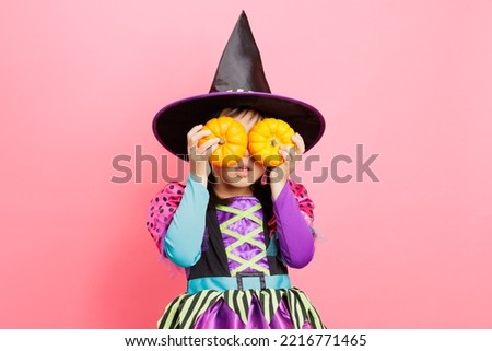 Happy Halloween! young girl with  witch costume and hold  small pumpkins against plain  background
