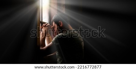 Tired pensive devote belief navy force young guy hero face cry hope hand pain love dark black old retro home room sun light text space Worry human feel lost despair frown upset warfare believe concept Royalty-Free Stock Photo #2216772877