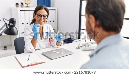 Middle age man and woman wearing doctor uniform holding covid-19 test at clinic