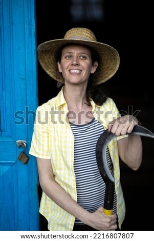 Smiling Female Farmer on Door with a sickle in Her Hands