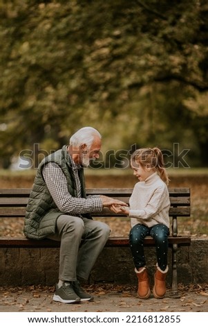 Handsome grandfather playing red hands slapping game with his granddaughter in park on autumn day Royalty-Free Stock Photo #2216812855