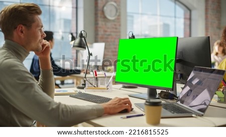 Portrait of White Creative Young Man Working on Green Screen Computer During the Day in Modern Busy Office. Project Manager Smiling While Using Desktop Computer.