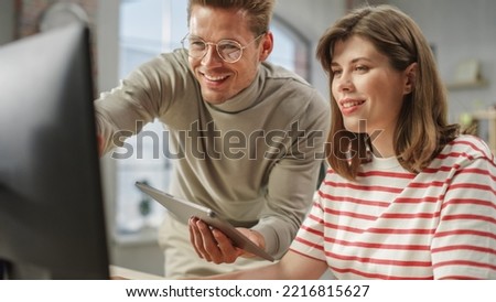 Portrait of Two Creative Colleagues Smiling and Discussing Work Using Computer and Tablet. White Male Brand Manager Consulting Young Female Caucasian Creative Director. Close Up Shot. Royalty-Free Stock Photo #2216815627
