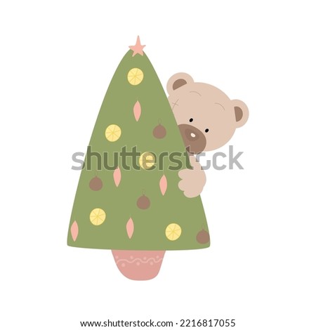Cute teddy bear peeking out of the Christmas tree.