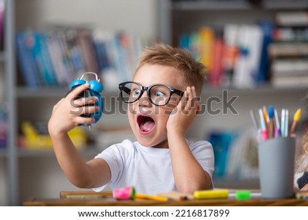School boy dreaming with alarm clock in classroom Royalty-Free Stock Photo #2216817899