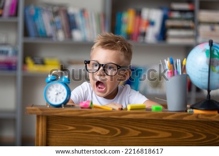 School boy dreaming with alarm clock in classroom Royalty-Free Stock Photo #2216818617