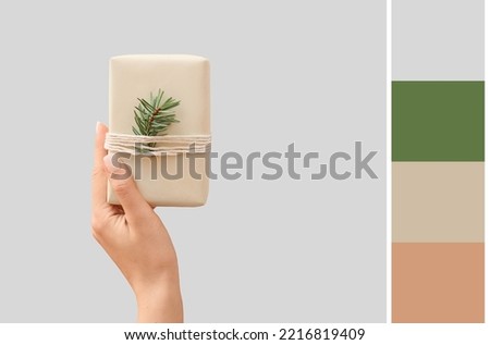 Female hand with Christmas gift on grey background. Different color patterns