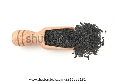  Black cumin seeds on a wooden spatula scattered over a white background                               Royalty-Free Stock Photo #2216822191