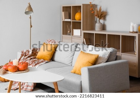 Interior of cozy living room with pumpkins, table and sofa