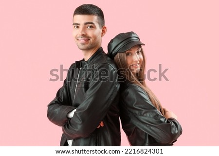 Fashionable young couple in autumn clothes on pink background