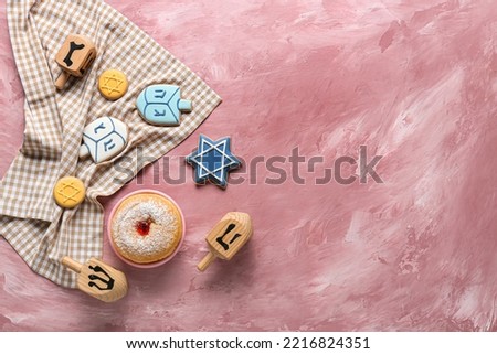 Wooden dreidels, napkin and food for Hanukkah celebration on color background