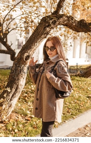 A stylish brunette woman walks around the autumn city. The season is autumn.