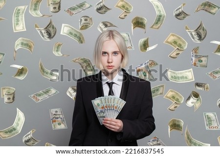 Concept photo of a successful woman standing under money rain isolated on grey background.