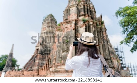 Young asian woman taking photo on his mobile phone camera of a beautiful landscape while standing near temple 