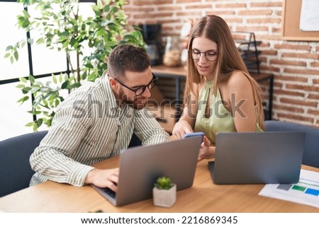 Man and woman business workers using laptop and smartphone at office