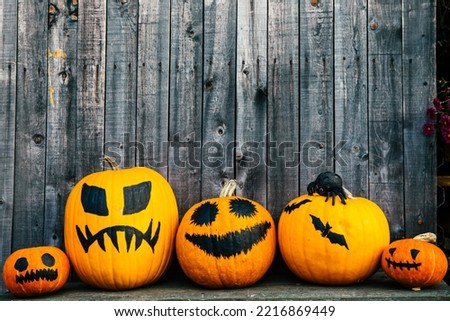 Halloween bright orange Jack-o-lantern pumpkins with black eyes and mouths on a dark wooden background with copy space