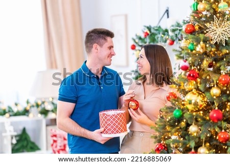 Portrait of a couple decorating a Christmas tree with balloons, hanging trinkets, A couple happily and positively spending time on New Year's holidays in a house with Christmas decorations, garlands