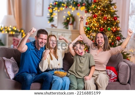 Merry Christmas. happy loving family is sitting on couch watching videos and having fun during the New Year holidays. Parents and children hug each other, are in the living room decorated for holiday.