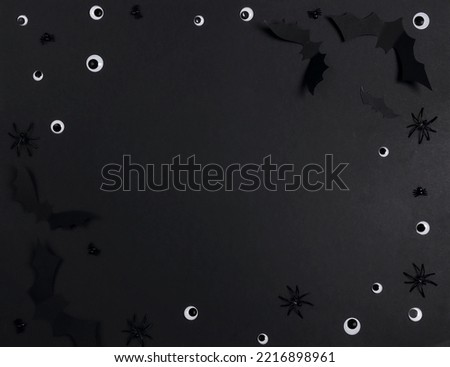 Halloween frame of paper bats, eyes and spiders on black background. Flat lay, top view, copy space.