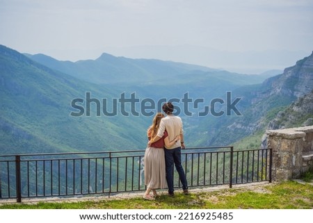 Happy couple tourists on background of Blue river running through green valley toward distant mountains. Beautiful mountains of Montenegro and the river Cievna
