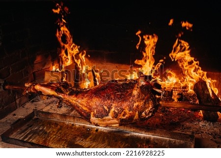 The lamb is cooked entirely on a spit on the fire. Cooking. Royalty-Free Stock Photo #2216928225