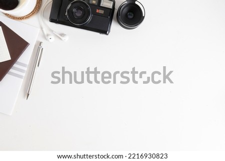 Top view creative working desk with camera, book, coffee cup and stationery on white table.