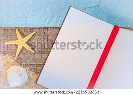 Open book without inscription seen from above on a wooden pavement above a pool with a starfish. Atmosphere vacations in summer.	