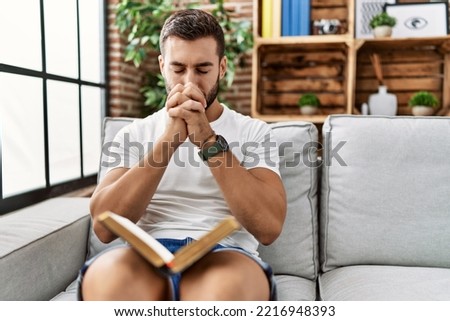 Young hispanic man smiling confident praying at home