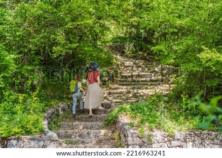 Mother and son tourists climb the mountain to the Ostrog temple. Monastery of Ostrog, Serbian Orthodox Church situated against a vertical background, high up in the large rock of Ostroska Greda
