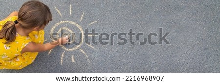 The child draws the sun on the asphalt. Selective focus. nature.