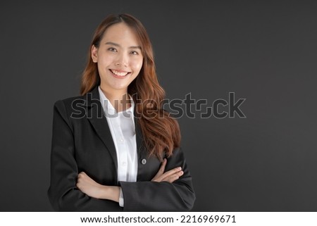 Business woman wearing a black suit Standing with arms crossed and smiling on a black background.