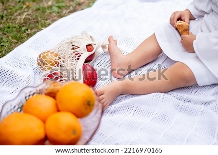 children's feet are bare on a picnic. prostylka on which fruits are oranges and apples. rest at nature
