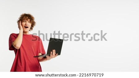Caucasian man's portrait isolated on white studio background. Emotional boy using laptop for studying. Concept of human emotions, facial expression, sales, online working, fashion.