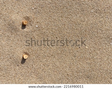 cigarette butts arranged as bullet points in sand on beach