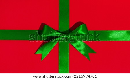 Green gift ribbon and bow on red paper background. High quality photo
