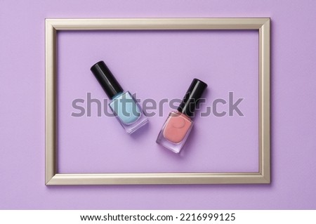 Nail polish bottles in a golden frame on pastel background. Minimal beauty concept. Top view