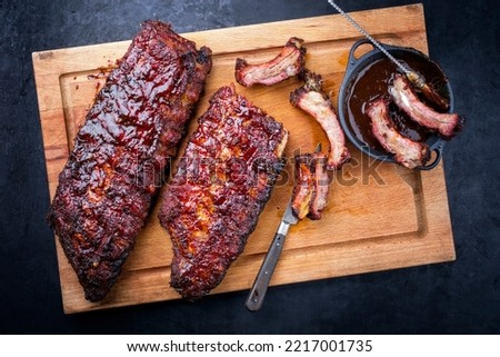 Barbecue pork spare loin ribs St Louis cut with hot honey chili marinade burnt as top view on a wooden cutting board  Royalty-Free Stock Photo #2217001735