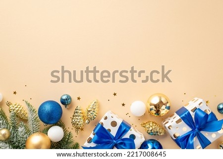 Christmas Day concept. Top view photo of pine cone ornaments white blue gold baubles gift boxes with ribbon bows fir branches in hoarfrost and confetti on isolated beige background with copyspace