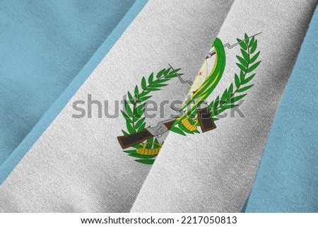 Guatemala flag with big folds waving close up under the studio light indoors. The official symbols and colors in fabric banner